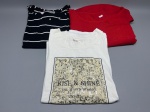 Lote composto por três camisetas femininas. A primeira, em malha azul marinho com listras horizontais brancas, manga curta e decote redondo, com barra arredondada; apresenta aspecto usado. A segunda, em malha vermelha lisa, manga curta e decote redondo. A terceira, em malha branca, manga curta, decote redondo com acabamento canelado, estampa frontal com inscrição 'Rise & Shine  This Is Your Moment' em painel texturizado bege e preto. Marcas não identificadas com clareza nas imagens. Tamanhos não verificados. Estado de conservação variável. blusa, top, camisa, peça casual, roupa feminina, conjunto de roupas