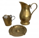 Conjunto antigo em latão composto por jarra, porta-copo vazado com cabo metálico e cinzeiro decorado com arabescos. Peças com pátina natural do tempo, marcadas e de boa presença decorativa. Ideal para compor ambientes vintage, coleções de metal antigo ou uso ornamental. No estado. Medida do maior 18cm.