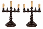 Par de candelabros antigos de estilo Manuelino, em madeira torneada e patinada em tom escuro, com hastes em espiral e elementos decorativos entalhados. Corpo com suportes para velas elétricas simulando castiçais antigos. Apresentam sinais do tempo e uso. Possui fiação, funcionamento desconhecido. Mede 55 x 35 cm.