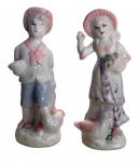 Par de esculturas em porcelana, representando menino e menina em trajes campestres, decoradas em policromia suave, com aves na base. Peças decorativas de delicado acabamento. Medida: 18 cm de altura.