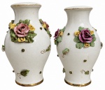 Par de vasos em faiança esmaltada, com decoração em relevo de rosas e folhagens policromadas, acabamento craquelê e detalhes dourados na borda e na base. Apresentam sinais compatíveis com o tempo e pequenas perdas nas flores aplicadas. Pequena diferença de tamanho entre um e outro. Maior: 21 cm de altura.