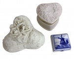 Lote composto por três delicadas peças em porcelana, sendo duas caixinhas e um pequeno recipiente decorado com rosas em relevo, além de peça em azul e branco com paisagem holandesa. Detalhes em pintura e douração. Sinal de restauro. Medida da maior: 11 cm.