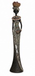 ÁFRICA - Escultura em resina representando figura feminina africana em traje cerimonial, ricamente ornamentada, com turbante e cesta sobre a cabeça, colares, pulseiras e vestido longo decorado com motivos e aplicações metálicas. Peça decorativa de expressiva presença. Possui dano no pescoço. Mede 43 cm de altura.