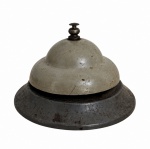 Antiga campainha de mesa, em metal, com acabamento patinado e marcas do tempo. Peça de caráter vintage, com botão superior de acionamento. Possui registro DELUXE 440 na base. Mede 7 x 10 cm.