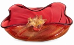 ITÁLIA  CRISTAL DE MURANO. Centro de mesa em denso cristal de Murano, na cor vermelho-rubi, com pigmentos dourados. Apresenta detalhe floral central em cristal transparente e borda ondulada de movimentos retorcidos. Mede 26 x 22 cm.