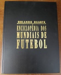 Livro Enciclopédia dos Mundiais de Futebol - Orlando Duarte - Capa Dura de LuxoExcelente obra de referência, consulta e pesquisa histórica indispensável para qualquer amante do esporte bretão: livro "Enciclopédia dos Mundiais de Futebol", escrito pelo lendário e saudoso jornalista Orlando Duarte. Um trabalho monumental de compilação de dados sobre o maior espetáculo da Terra. Autor: Orlando Duarte. Acabamento: Capa dura de luxo com letras gravadas em dourado (hot stamping). Conteúdo Temático: A obra funciona como um inventário estatístico completo de todas as Copas do Mundo. Traz fichas técnicas detalhadas de todos os jogos, escalações oficiais de todas as seleções, número de pagantes, árbitros, autores dos gols, curiosidades de bastidores e o balanço político e social de cada edição do torneio mundial.Estado de Conservação (Conforme Fotos): Capa e Contracapa: Encadernação original em capa dura preta muito bem preservada. Apresenta discretíssimos sinais de armazenamento em prateleira e manuseio suave. As gravações douradas com o nome do autor e o título mantêm excelente brilho e nitidez, sem desgastes na tipografia. Miolo: Perfeito estado de conservação interna. Páginas totalmente firmes ao dorso, completas, limpas e perfeitamente integras, livre de rabiscos modernos, assinaturas de posse, rasgos ou furos de traça.