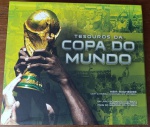 Livro Interativo Tesouros da Copa do Mundo - Keir Radnedge - Panda Books (Com Réplicas e Envelopes)Fascinante e luxuosa obra de colecionador que traz a história do futebol literalmente em suas mãos: livro "Tesouros da Copa do Mundo", escrito pelo célebre historiador esportivo Keir Radnedge. Publicado sob os auspícios e consultoria do prestigiado Museu Nacional do Futebol de Manchester. Autor: Keir Radnedge. Editora: Panda Books. Formato: Panorâmico de luxo com capa dura e páginas em papel couchê grosso de alta gramatura. Diferencial de Colecionismo (Livro Interativo): O grande atrativo da obra é a inclusão de dezenas de fac-símiles e réplicas exatas de memorabília histórica acondicionadas em envelopes temáticos colados nas páginas. Inclui reproduções de ingressos de finais históricas, cartazes oficiais de época (como o da Copa de 1954), relatórios confidenciais da FIFA e réplicas de figurinhas raras (como a da constelação de 1970). Conteúdo: Cronologia ricamente ilustrada cobrindo todas as Copas do Mundo, tabelas de campeões, dados sobre a evolução das bolas, uniformes e medalhas, além de crônicas sobre craques como Pelé, Maradona e Puskás.Estado de Conservação (Conforme Fotos): Capa e Contracapa: Capa dura original muito bem conservada, com excelente brilho e nitidez nas imagens (destacando o icônico capitão Cafu erguendo a taça em 2002). Apresenta discretíssimos sinais de armazenamento nas bordas. Miolo: Impecável. Páginas firmes, limpas, sem rabiscos ou rasgos. Todos os envelopes interativos internos encontram-se presentes, com as réplicas de documentos e mementos históricos preservadas em seu interior.