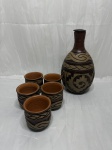 Jarra com 5 copos em cerâmica trabalhado com relevos. Medindo a garrafa 14cm de bojo x 26cm de altura, copos 8cm x 8cm de altura. Tampa da garrafa com leve bicado.