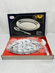 Travessa oval rasa com colher de servir em aço inox. Medindo a travessa 31cm x 21cm.