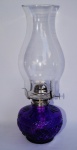 Espetacular lampião de querosene com base em vidro trabalhado tom violeta e manga em vidro transparente. Medida 65 cm de altura.
