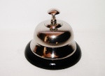 Campainha de metal tipo sineta com acionamento por botão superior com a base em formato arredondo na cor preto. Peça sem uso e na caixa original.