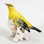 Pássaro em porcelana alemã  `Karls Ens` Volksted, pousada sobre tronco, com bela anatomia e plumagem nas cores amarelo e preto, cerca 1920/30. Meds: 19,5 cm x 19,0 cm