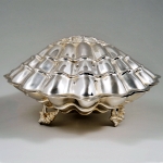 Porta caviar em metal espessurado à prata em formato de grande concha com recipiente interno em vidro. Meds: 12, 5 cm x 21,0 cm x 22,0 cm