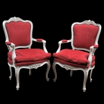 Par de cadeiras de braço em estilo francês em madeira com pintura branca com fino entalhe floral e acantos no encosto, saia e pernas, estofada e forrada com veludo vermelho, pernas levemente arqueadas. Meds: 1,02 m x 63,0 cm x 67,0 cm