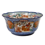 Bowl em porcelana japonesa Imari com rica decoração e reservas em rouge de fer, azul, vermelho e verde com detalhes em dourado, reservas com paisagens, elementos vegetais, dragões e cães de fó, borda ondulada, cerca 1900 . Meds: 12,5 cm x 27,0 cm