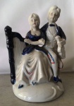 Casal em porcelana com harpa em detalhes azul . Mede: 19 x 13 cm