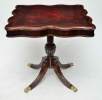 Mesa inglesa em mogno no estilo George III com tampo em couro pirogravado, borda ondulada, base em quatro pés terminados em sapatas de bronze. Med.: 70x74x74 cm.