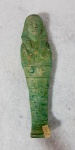 Ushabti egipcio em faiança verde clara, período e dinastia não identificados. O cartucho com o nome está parcialmente danificado (pé). Med. 14 cm.