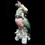 Cacatua em porcelana alemã `Kals Ens` Volksted com fina e bela anatomia e plumagem, pousada sobre tronco, marcada no fundo. Altura: 27,0 cm