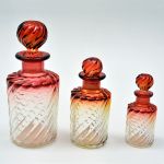 Conjunto de 3 perfumeiros em cristal Baccarat rosa e branco, corpo cilíndrico com relevo de gomado torcido e pescoço em formato de carretel, século XIX. Altura: 17,5 cm (o maior)