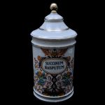 Pote de farmácia em porcelana européia com rica pintura de anjos, querubins, pássaros, ramos e folhas, reserva oval com inscrição `SUCCINUM RASPUTUM`. Altura: 27,0 cm