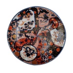 Medalhão em porcelana japonesa Imari com rica decoração nas cores rouge de fer, vermelho, azul e dourado, com reservas de leques, catavento, aves. Peonias e crisantamos, século XIX. Diametro: 46,7 cm