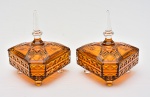 Par de lindas bombonieres "triangulares" em demi cristal âmbar decoradas com geométricos em relevo, pegas das tampas em forma de prisma. Med.: 21x20 cm.
