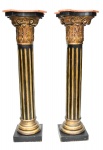 Par de importante colunas palacianas, "Revolution", em madeira ebanizada e realçada à ouro, fustes gomados com capitéis entalhados. Tampos em mármore fiorentino. Med.: 142x45x45 cm.