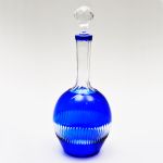 Garrafa em cristal da Bohemia com `overlay` azul, bojo globular com longo pescoço facetado. Altura: 32 cm.
