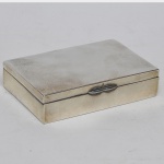 Caixa porta cigarros em prata de lei, interior e fundo em madeira. No estado: Pequenas mossas. Peso bruto: 543 g. Med.: 6,5 x 10 x 16 cm.