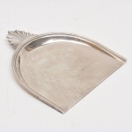 Cata migalhas em metal espessurado a prata, marca Christofle, medindo 23,5 x 21 cm.
