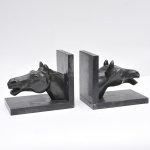 Par de serres livres em petit bronze representando cabeças de cavalos. Base em granito negro. Medindo 20 cm de largura e 17 cm de altura,