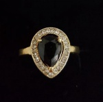 BIJUTERIA FINA- Lindo anel em metal dourado, em formato de gota, cravejado por pedras brancas, galeria central composta por linda pedra na cor preta. Aro. 22