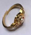 Belíssimo bracelete com suporte para caixa de relógio na cor dourada, cravejado por zircônias nas cores brancas, verdes e vermelhas. Galeria central composta por pérola.