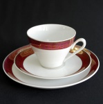Conjunto composto por xícara de chá, pires e prato pão em Porcelana Branca com delicado barrado próximo a borda em tons de rouge e dourado.
