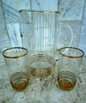 Anos 60 : conjunto de Jarra e dois longos copos em vidro translúcidos com finas listras em ouro velho . Altura da Jarra 26 cm e dos copos 14 cm.