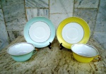 Duas xícaras em porcelana MAUÁ de chá esmaltadas e vitrificadas com faixas amarelas e verde água ambas , bem claras, com frisos dourados. Diâmetro da xícara 10 cm e do pires 15 cm.