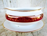 Molheira com presentoir acoplado em porcelana esmaltada na cor branca e vitrificada com faixas bourdeaux , detalhes e arabescos em ouro . Altura 9 cm e comprimento 19 cm. Marca da porcelana MAUÁ