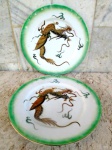 Par de medalhões decorativos em porcelana esmaltada no tom verde degradée e vitrificada com aplicação de figura de dragão exótico em alto relevo na cor castor com ouro brunido. Diâmetro 26,5 cm.