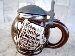 Tankard  - Caneco de coleção , bojudo em faiança esmaltada no tom marrom , com tampa em pewter tendo figura de frade em alto relevo. No seu bojo decoração de cenas de taberna e tábuas no estilo medieval com inscrições Peça da década de 70 que pertenceu ao restaurante Franciscano em São Paulo. Altura  14 cm e 34 cm de circunferência.