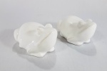 GRIFE SECRET DE FAMILE - Duas esculturas de sapinhos em porcelana branca. Com etiqueta no fundo. Med. 9 x 6.5 x 7 cm