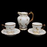 Conjunto de leiteira e duas xícaras com pires em porcelana francesa velho paris, decorada com relevos e alça em elementos fitomorfos com pintura a ouro. Alt: 12,0 cm