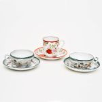 3 xícaras com pires em porcelana japonesa, sendo duas com paisagem, pesonagens e pagodes e uma com elementos florais.
