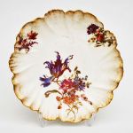 Prato em porcelana francesa de limoges com pintura floral e baixo relevo de concheados com borda recortada e dourada. Diam: 23,5 cm