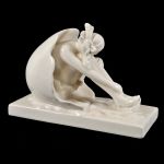 Escultura Art Decó em faiança manufatura L & V Ceram, representando figura feminina sentada dentro de casca de ovo, marcada no fundo. Meds: 26,0 cm x 11,5 cm x 18,0 cm