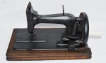 Antiga máquina de costura co base em madeira com marchetaria. Lote está sendo vendido para cobrir despesas de guarda e depósito de cliente que não retirou a peça de leilões anteriores.