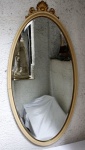 Antigo Espelho bisotado chipandelle em madeira nobre entalhada em formato oval encimada por florão. Possui pátina na cor marfim. Medidas: 144 x 71 cm com florão