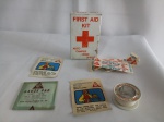 Caixa primeiros socorros, FIRST AID KIT, americana, embalagem original papelão, contém diversos itens, apresenta desgastes; aprox. 10,5 x 6,5 x 2,5cm