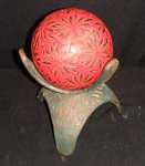 Interessante Objeto decorativo com base de ferro, parte superior esfera em vidro revestida em laca vermelha com tema florais. Alt. 18cm