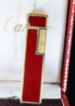 "CARTIER". ISQUEIRO CARTIER VERMELHO COM DETALHES EM DOURADO . ACOMPANHA CAIXA ORIGINAL. PESO 42.9 GRAMAS MEDINDO 6.2CM X 1,4CM. NÃO FUNCIONA